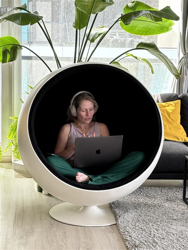 Fruzsina working on her laptop in a cocoon ball chair at home, surrounded by plants